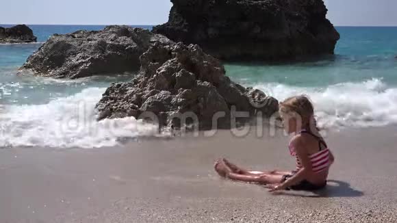 4K孩子在沙滩上玩耍孩子在海滨的波浪中玩耍女孩在海岸上建造城堡湾视频的预览图