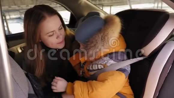 一位母亲和一个小儿子坐在车后座上的肖像他们拥抱着视频的预览图