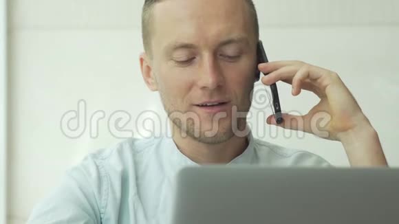 一个年轻的商人在电话上讲话在笔记本电脑上看电子邮件视频的预览图