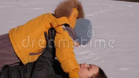 特写一位幸福的母亲和一个小儿子躺在雪地里拥抱视频的预览图