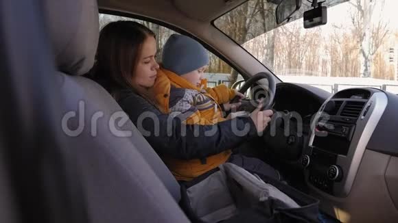 一个男孩坐在他妈妈车上拿着方向盘视频的预览图