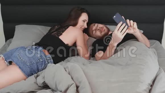 年轻幸福的已婚夫妇调情躺在床上女人和男人在卧室里休息自拍和亲吻视频的预览图