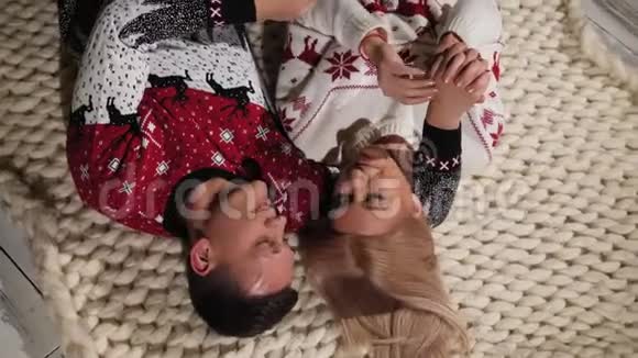 幸福的年轻夫妇躺在家里的地板上圣诞节庆典上景视频的预览图