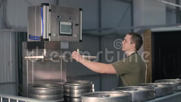 一名男性啤酒师使用自动啤酒桶灭菌机清洗和消毒啤酒桶啤酒生产视频的预览图