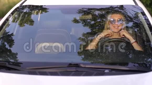 夕阳西下一个戴着墨镜的金发女郎坐在车后的画像视频的预览图