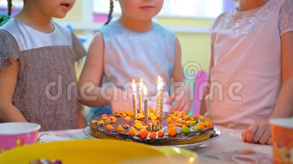 可爱的小女孩在节日蛋糕上吹蜡烛视频的预览图