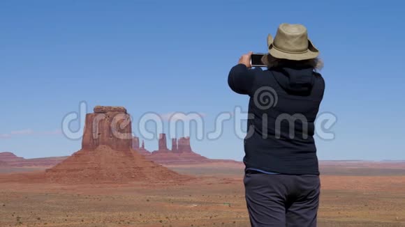 站在古迹谷顶的女人在智能手机上拍照视频的预览图