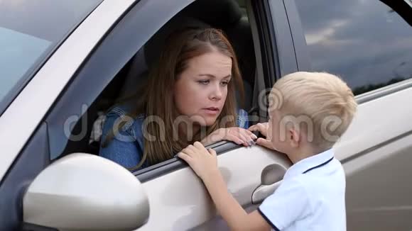 一个小男孩和坐在车里的母亲说话的特写镜头视频的预览图