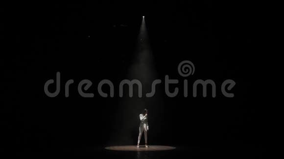 一位带着麦克风的歌手在聚光灯下的黑暗中在舞台上唱歌视频的预览图