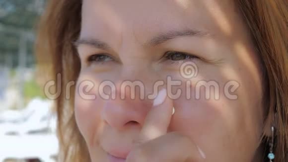 女孩站在沙滩上用防晒霜涂抹她的脸部皮肤视频的预览图