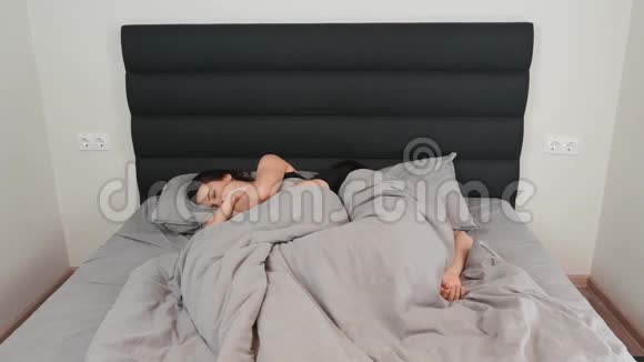 女人和男人躺在床上睡觉年轻的幸福家庭夫妇在家里睡在灰色的床上快乐的关系已婚夫妇视频的预览图