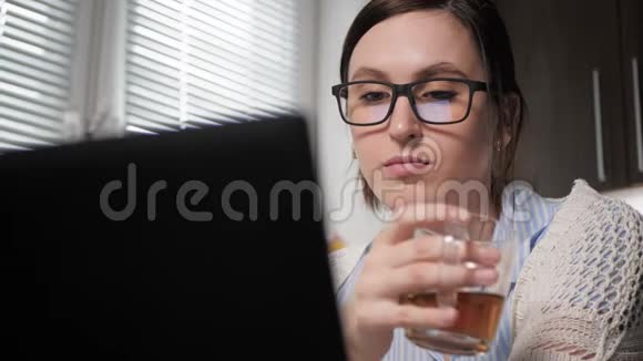 女孩喝绿茶或红茶厨房里貌美的女人的特写镜头看着笔记本电脑屏幕视频的预览图