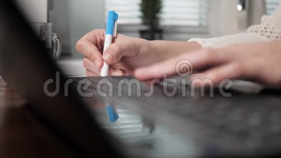左手在笔记本电脑键盘上打字右手在笔记本上用圆珠笔写东西视频的预览图