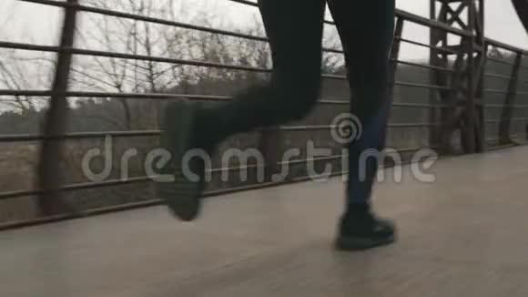 女腿跑户外特写后景女人的脚正在公园里慢跑在桥上过河运动和跑步概念视频的预览图