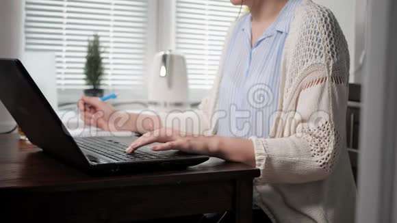 自由职业者的工作理念年轻女子戴着漂亮的眼镜在厨房里工作手提电脑打字视频的预览图