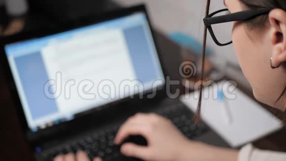 模糊的女手女孩带着眼镜在晚上在笔记本电脑键盘上打字看着屏幕女自由职业者视频的预览图