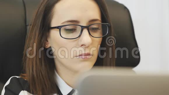 晚上疲惫的女性脸在办公室里用笔记本电脑工作辛苦工作一天后女人把眼镜摘下来肖像视频的预览图