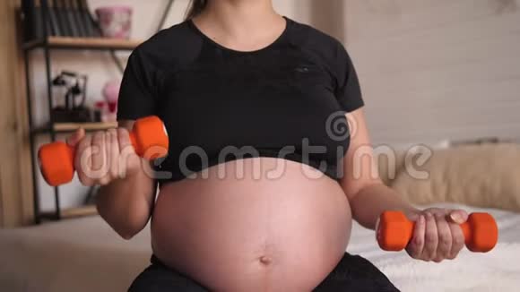 孕妇在床上坐在家里做哑铃运动视频的预览图