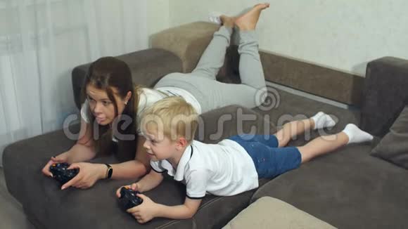 情感肖像的母子在家里的沙发上他们玩电子游戏视频的预览图