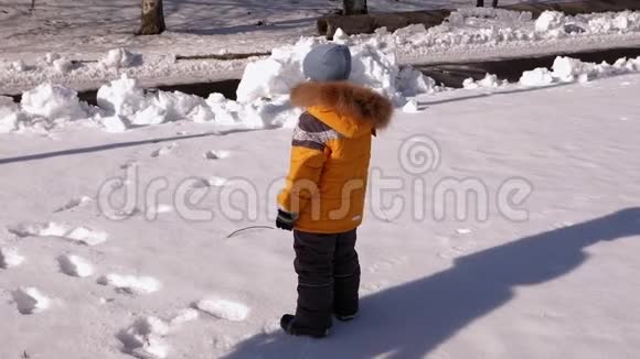 一个小男孩在一个覆盖着雪的公园里玩他跳着落在雪上视频的预览图