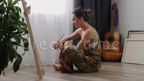 有才华的女艺术家在现代家庭从事抽象绘画在阳光明媚的日子里年轻女子在家中画画布视频的预览图