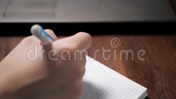 女人用钢笔在笔记本上写东西旁边是笔记本电脑特写慢动作视频的预览图