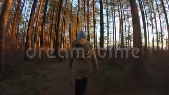 日落或日出时在树林里散步的女孩后视跟拍慢动作视频的预览图