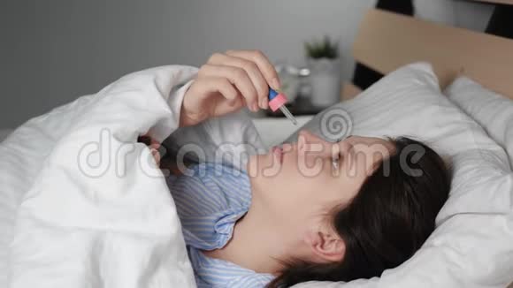 生病的女人流鼻涕躺在毯子下面的床上用吸管滴鼻涕感冒流感过敏视频的预览图