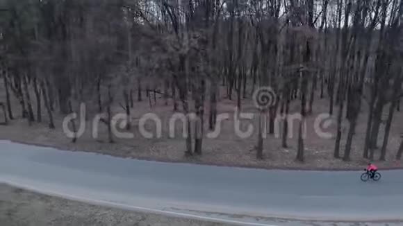 运动员在森林中的空车路上快速密集地骑着公路自行车孤立的自行车骑行戴着头盔的赛克丽斯视频的预览图