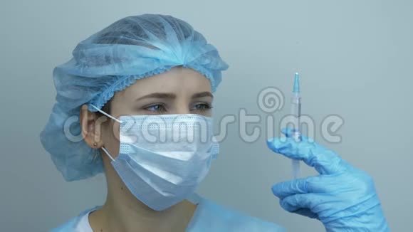 女护士持注射器注射用药物的肖像柯维德19冠状病毒的大流行保护病毒防护视频的预览图