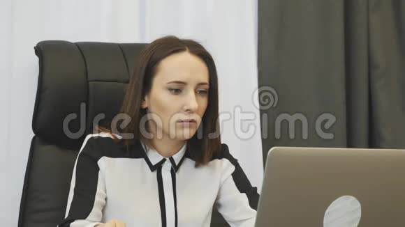 上班喝咖啡的女人年轻的女商人一边在办公室喝咖啡一边在笔记本电脑上工作女老板吃咖啡面包视频的预览图