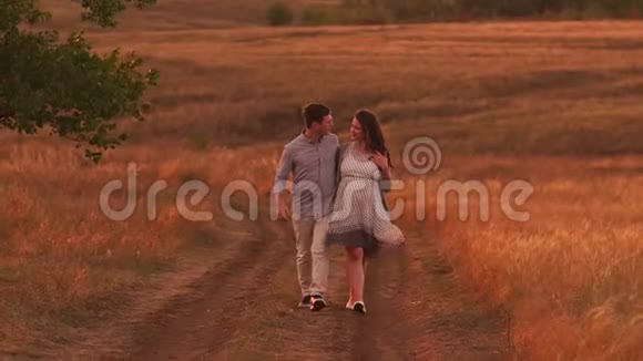 幸福的孕妇和她的丈夫在日落时沿着乡间小路散步视频的预览图