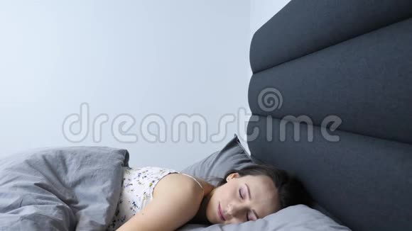 年轻的女性早上在客厅醒来害羞微笑的女人躺在床上在家醒来快乐的女孩视频的预览图