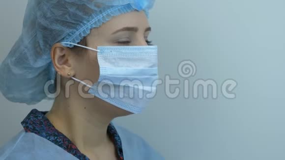 妇女脱下防护性医用面罩的肖像特写年轻的女科学家摘下医用蓝色面具re医生视频的预览图