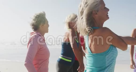 年长的女人在海滩上伸展视频的预览图