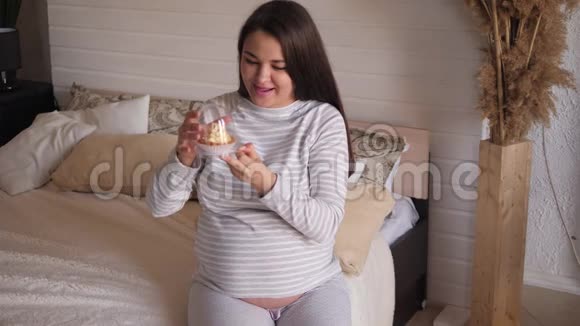 一位孕妇打开一个盒子在家里的床上放着一个漂亮的甜蛋糕视频的预览图