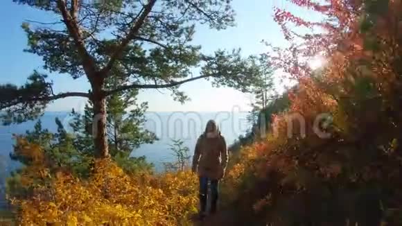 阳光明媚的秋日女孩爬上海边陡坡上的小径视频的预览图