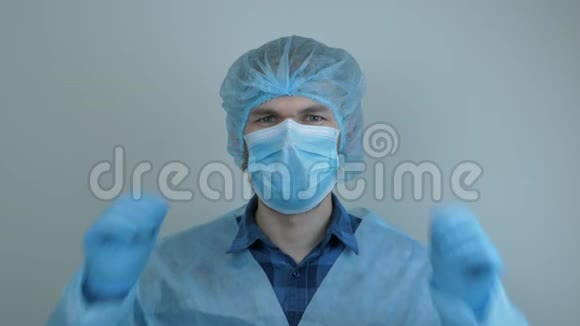 戴防护医疗用具的人在手术后摘下医疗面罩男性医生戴蓝色医用口罩感染病毒视频的预览图