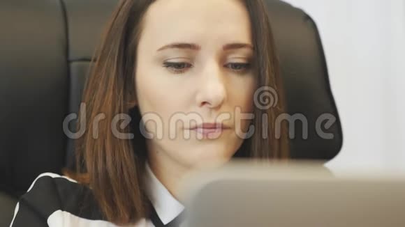 专注的女人在用笔记本电脑工作前戴上眼镜在笔记本电脑屏幕上看到的女性脸部特写自信的企业形象视频的预览图