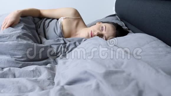 女人一个人在家里的空床上醒来年轻的女性独自在酒店房间醒来心烦意乱的孤立女孩躺在空床上隆隆视频的预览图