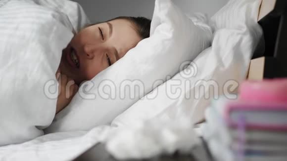 生病的女人流鼻涕躺在毯子下面的床上用纸巾吹鼻涕感冒流感过敏灰尘猫毛视频的预览图