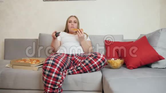超重的女孩吃披萨看电视视频的预览图