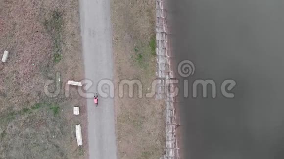 骑自行车者在大坝附近无人驾驶视图穿着自行车服装的女人骑着砾石自行车在户外骑自行车专业三项运动员硬脚踏板视频的预览图