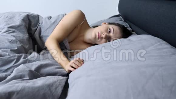 一个人躺在床上让孤独的女人心烦意乱孤独的年轻女性独自在家醒来不快乐的女孩独自躺在床上视频的预览图