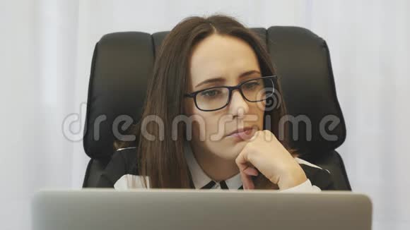 女商人考虑她在办公室的工作年轻的集中妇女穿着白色衬衫在现代办公室的笔记本电脑上工作港口视频的预览图