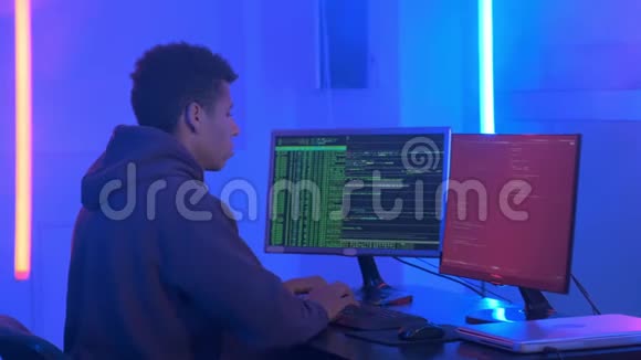 中镜头非洲年轻人在黑暗的房间里用霓虹灯写黑客程序视频的预览图