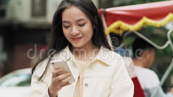 微笑的年轻女子看着手机视频的预览图