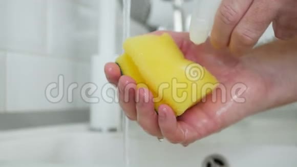 男人手里拿着用清洁剂和大量泡沫浸泡的洗碗海绵视频的预览图