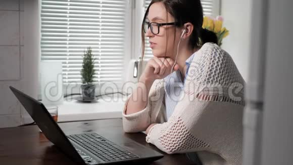 自由职业者的工作理念漂亮的年轻女人戴着眼镜和耳机看着笔记本电脑她在视频的预览图