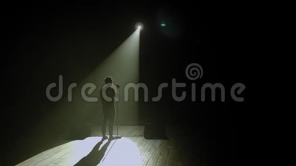 一个男人在黑暗中拿着麦克风上台的剪影发言人视频的预览图